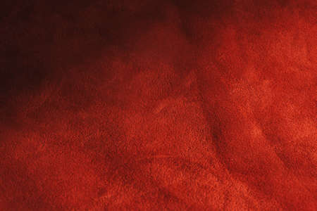 Red matte background of suede fabric, closeup. Velvet texture of seamless leather. Felt material...