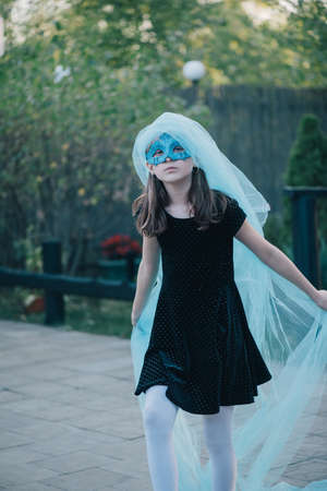The beautiful young girl in a mysterious mask. Girl in a blue carnival mask. Teenager and blue clothの写真素材