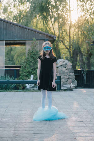 The beautiful young girl in a mysterious mask. Girl in a blue carnival mask. Teenager and blue clothの写真素材