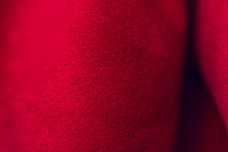 Red matte background of suede fabric, closeup. Velvet texture of seamless leather. Felt material macro. Red suede texture. Fabric, leather, material for designers.の写真素材
