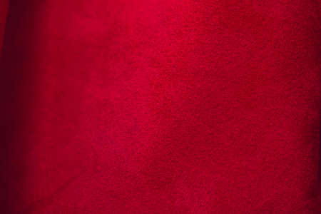 Red matte background of suede fabric, closeup. Velvet texture of seamless leather. Felt material macro. Red suede texture. Fabric, leather, material for designers.の写真素材