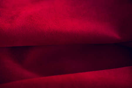 Red matte background of suede fabric, closeup. Velvet texture of seamless leather. Felt material macro. Red suede texture. Fabric, leather, material for designers.の写真素材
