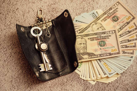 Keys and money. Dollars and apartment keys. dollars on which are the keys to the apartment. the concept of saving and buying an apartmentの写真素材