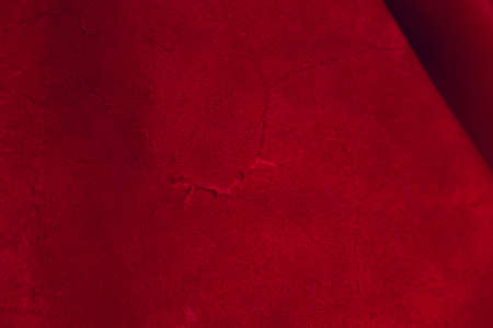 Red matte background of suede fabric, closeup. Velvet texture of seamless leather. Felt material macro. Red suede texture. Fabric, leather, material for designers.の写真素材
