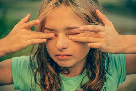 Beautiful sad little girl crying, on summer background. Girl crying. Portrait of a sad girl close up