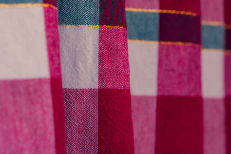 picnic cloth. The checkered tablecloth on a table. Texture of white fabric in a red cell. Background...