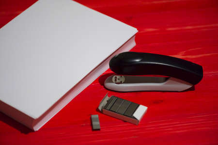 Black office stapler i Stationery for paper stitching. Stapler and staples with sheets of paper on a...