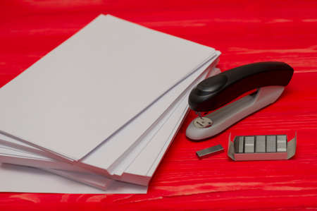 Black office stapler i Stationery for paper stitching. Stapler and staples with sheets of paper on a...