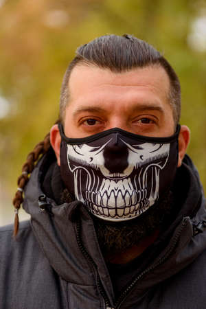 man in winter clothes on the street with a medical face mask on. Closeup male in a respirator to...