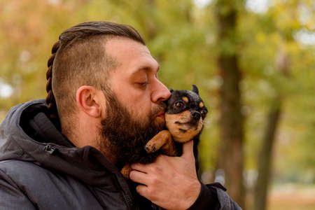 Man with beard and chihuahua. A man in the park with his beloved pet in his arms. Guy with dog