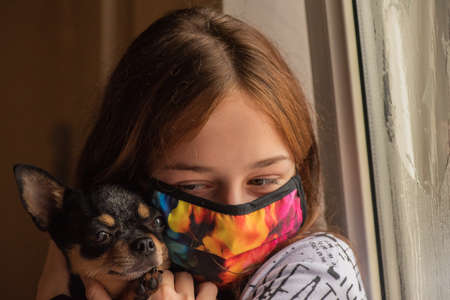 Girl with her chihuahua out the window because she cannot go outside. Lifestyle concept. Girl and dog coronavirus stay home. Girl 9 years old with a chihuahua dog during a viral infection. Corona virusの写真素材
