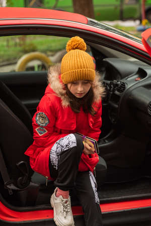 passenger, teenager model. Teenage girl in a red car. Girl in a yellow hat and red jacket