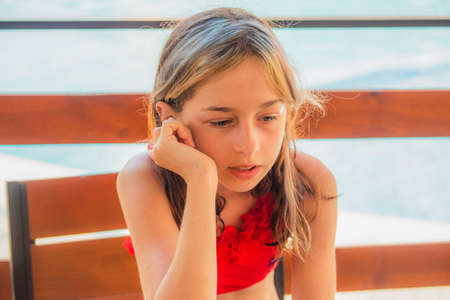 Girl child in swimsuit near the pool, the concept of rest and vacation. Teenage girl near the pool. Teenager girl 10 years old in a red swimsuit. Summer vacation conceptの写真素材