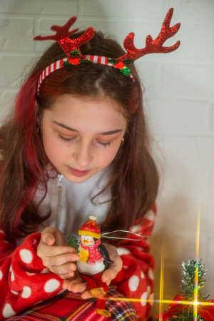 Portrait of happy girl looking at decorative toy ball by Christmas tree. Girl and Christmas tree.