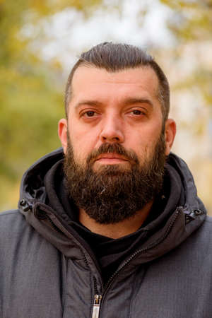 Man with a beard in a gray jacket on the street. Portrait of a man. The guy with the beard.の写真素材