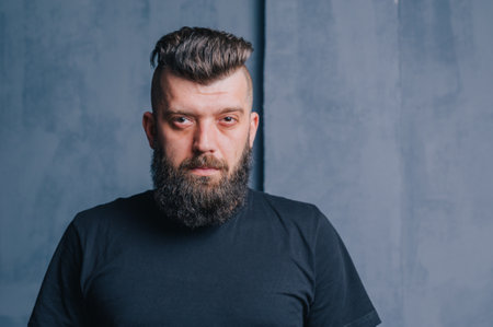Stylish bearded hipster male. Portrait of a brunette man with a beard in the studio. Stylish haircut for a man.の写真素材