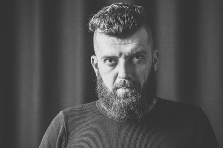 Stylish bearded hipster male. Portrait of a brunette man with a beard in the studio. Black and white