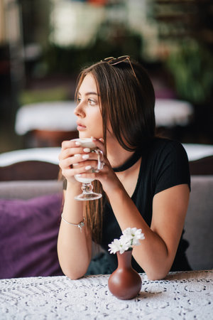 pretty young woman sitting in a cafe with a cup of coffee latte. Brunette girl in cafe with latte.