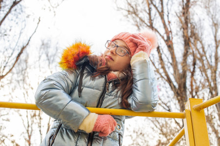 Young beautiful woman wearing winter clothing. Teenage girl in a jacket and hat. School age girl.