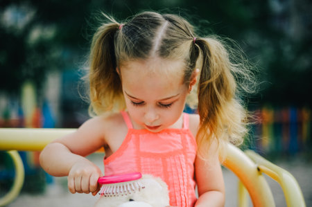 Adorable girl in dress swing on playground in park. Little girl in dress on the playground in summerの写真素材