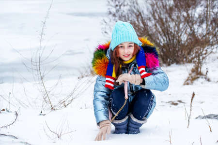 Winter portrait of young girl in her warm clothing. Teenage girl in a blue hat. snowy weather.の写真素材