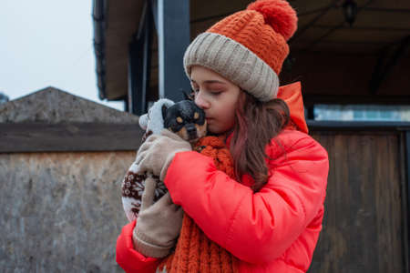 Girl 10 years old. Teenager girl in orange jacket, hat and scarf. Girl and chihuahua.の写真素材