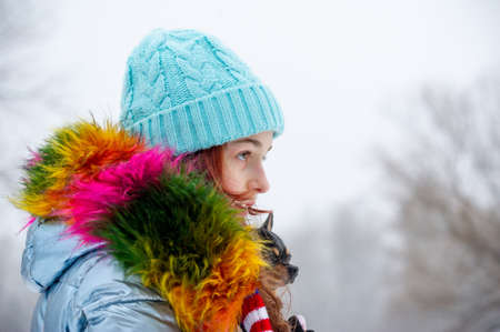 Winter portrait of young girl in her warm clothing. Teenage girl in a blue hat. Girl with chihuahuaの写真素材