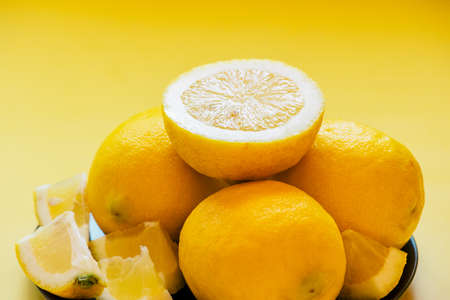lemons on a black plate on a yellow background. Background. citrus, fruit