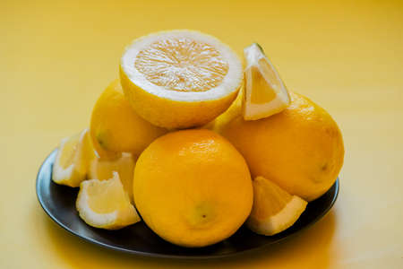 lemons on a black plate on a yellow background. Background. citrus, fruit organic, healthy,の写真素材