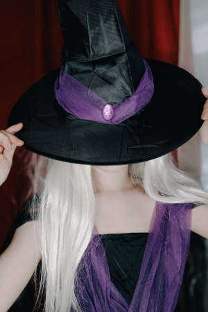 girl 10 years old indoors. Teen girl. Teenager girl covering her face with hat, halloween conceptの写真素材