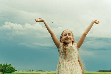 A little girl in a white dress with a flower stands in the summer in the garden. in summerの写真素材