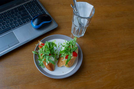 Healthy sandwich on office table. Laptop on the table and a sandwich. Computer and food