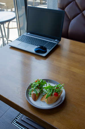 Healthy sandwich on office table. Laptop on the table and a sandwich. Computer and foodの写真素材