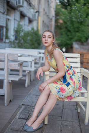 girl in dress walks through the old town in the summer. Beautiful blonde woman summer photo.の写真素材