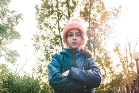 Portrait. The girl folded her hands in front of her. Child in blue jacket and pink hat clothesの写真素材