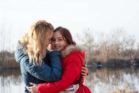 Mom gently hugs her daughter. Mother and daughter family time on a walk by the river.の写真素材