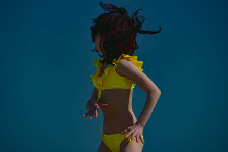 girl on a background of a summer sky on a sultry day. The girl runs in a yellow swimsuit. vacationの写真素材