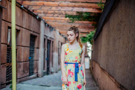 girl in dress walks through the old town in the summer. Beautiful blonde woman summer photo.の写真素材