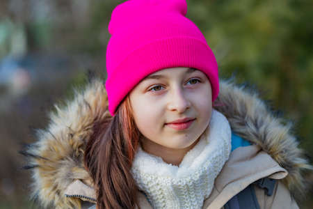 Outdoor portrait of adorable girl in a pink hat. Schoolgirl girl in a beige jacket. A schoolgirlの写真素材