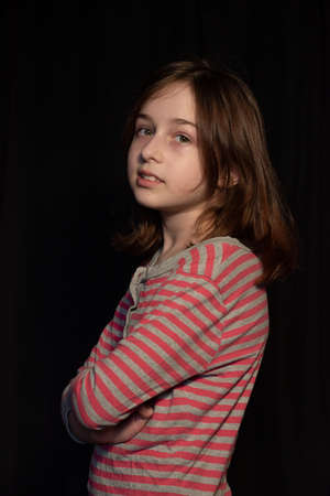 young beautiful girl in a pajamas on black background. Portrait of a girl in pink striped pajamasの写真素材