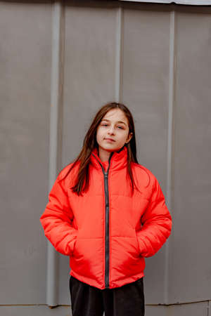 photo of teenage girl on a gray wall background. Teenager girl in orange jacket. portrait,の写真素材