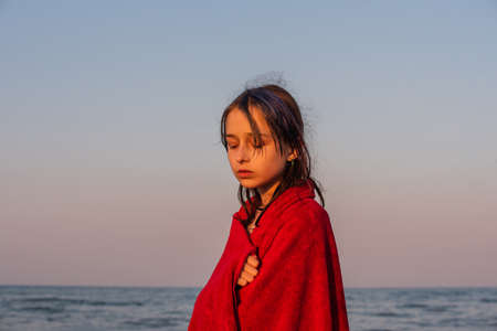 Girl in a red towel at the sea. Teenager girl at the sea. Rest, vacation. at sunset by the sea.の写真素材