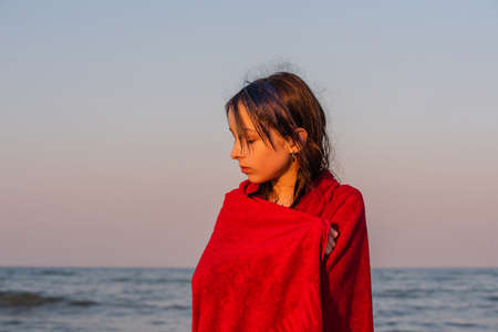 Girl in a red towel at the sea. Teenager girl at the sea. Rest, vacation. at sunset by the sea.の写真素材