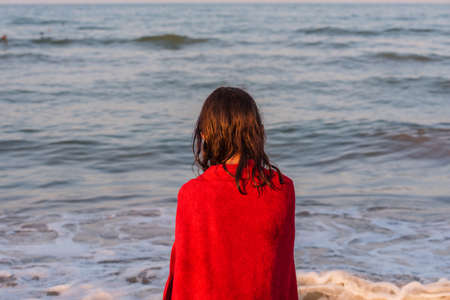 Girl in a red towel at the sea. Teenager girl at the sea. Rest, vacation. at sunset by the sea.の写真素材