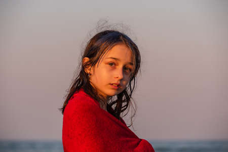 Girl in a red towel at the sea. Teenager girl at the sea. Rest, vacation. at sunset by the sea.の写真素材