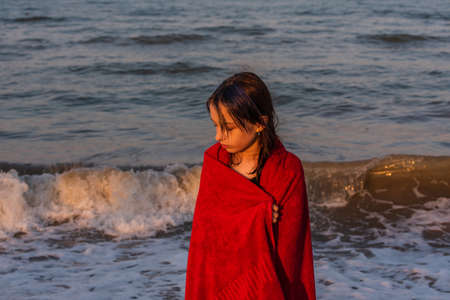 Girl in a red towel at the sea. Teenager girl at the sea. Rest, vacation. at sunset by the sea.
