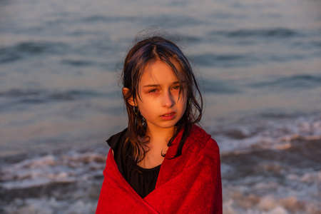 Girl in a red towel at the sea. Teenager girl at the sea. Rest, vacation. at sunset by the sea.の写真素材