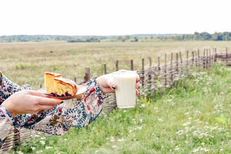 glass of milk. A female hand holds a glass with milk on the background of the field. Milk dayの写真素材