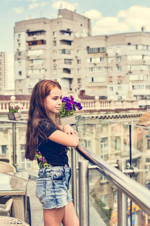 Teenager girl in a black T-shirt. Girl 10 years old posing on the veranda in a cafe.の写真素材