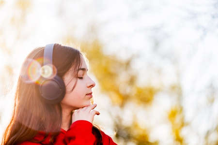Happy girl listening to music with headphones in a park. Teenage girl in wireless headphones.の写真素材